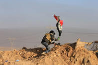 A member of the federal police forces puts up an Iraqi flag at a position during a battle with Islamic State militants in south of Mosul, Iraq. REUTERS/Alaa Al-Marjani