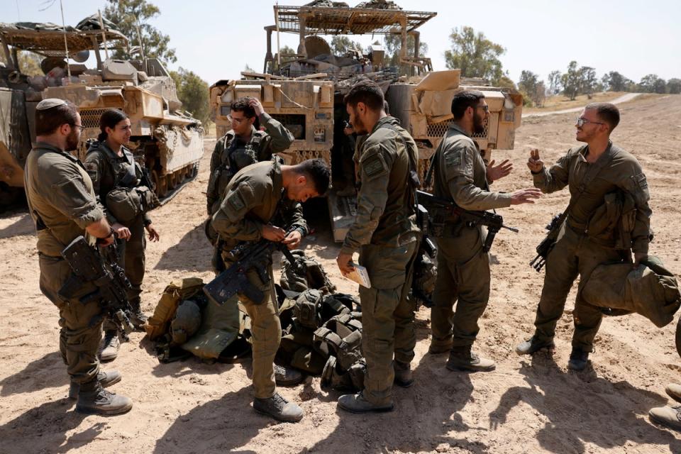 Israeli soldiers stand next to military vehicles, near the Israel-Gaza border (Reuters)