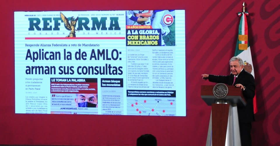 AMLO mostrando portada del diario Reforma sobre consultas en estados