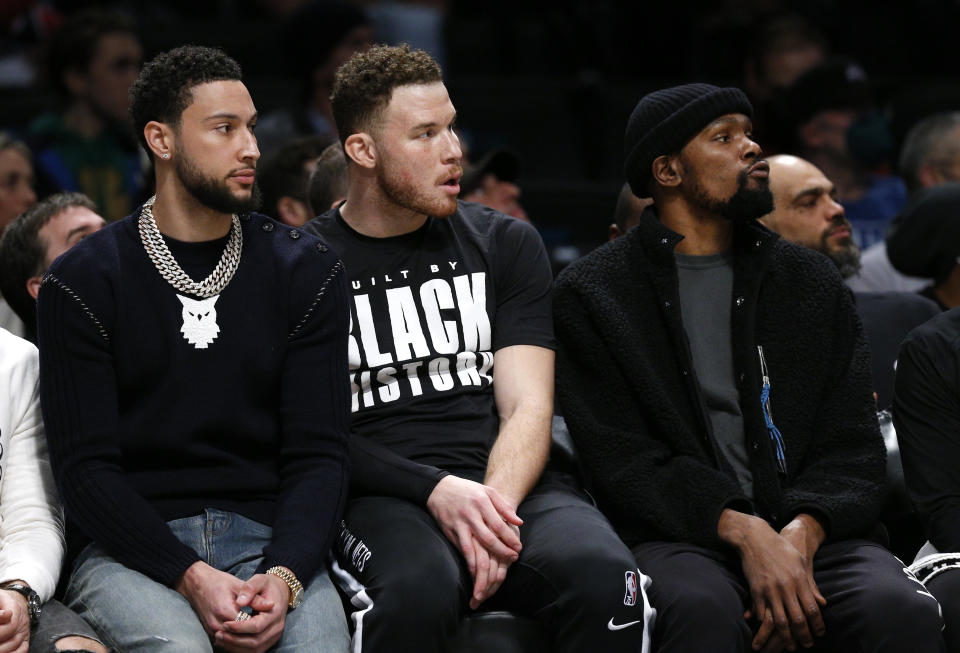 Brooklyn Nets' Ben Simmons, Blake Griffin and Kevin Durant watch teammates play against the Boston Celtics during the first half of an NBA basketball game Thursday, Feb. 24, 2022, in New York. (AP Photo/Noah K. Murray)