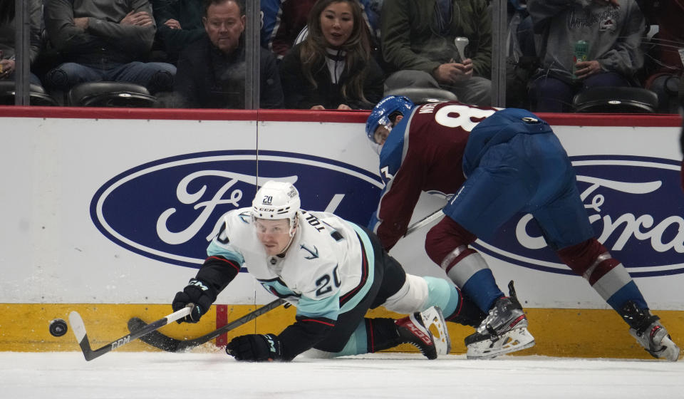 Seattle Kraken right wing Eeli Tolvanen, left, reaches for the puck after being hit by Colorado Avalanche left wing Matt Nieto in the first period of an NHL hockey game Sunday, March 5, 2023, in Denver. (AP Photo/David Zalubowski)