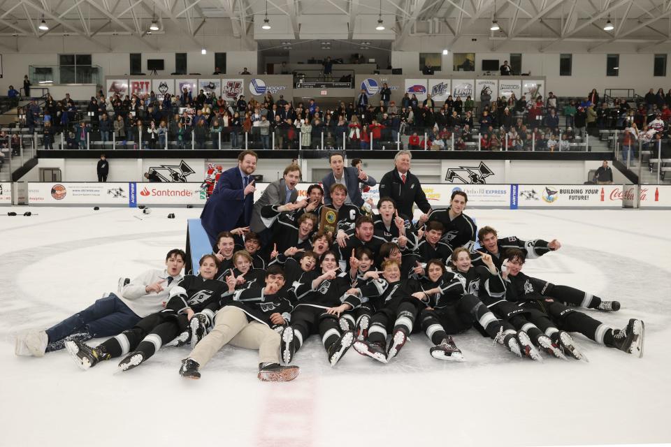 Coaches and players of the Division II champion Rogers/Middletown/Tiverton co-op hockey team pose for a team photo on the Schneider Arena ice after defeating Portsmouth 3-1 on Saturday afternoon in Providence. It was the first-ever title for the Hurricanes.