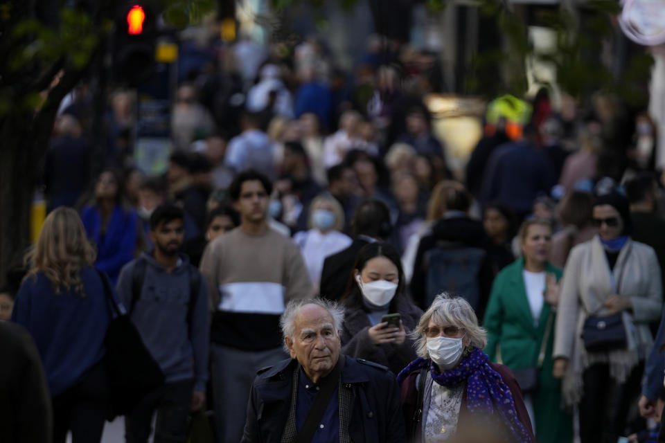 FILE - People wearing face masks walk along the Oxford Street shopping area of central London, Oct. 20, 2021. As countries across Europe reimpose lockdowns in response to surging COVID=19 cases and deaths, the UK – long one of Europe’s hardest-hit countries -- carries on with a policy of keeping everything as normal as possible. (AP Photo/Matt Dunham, File)