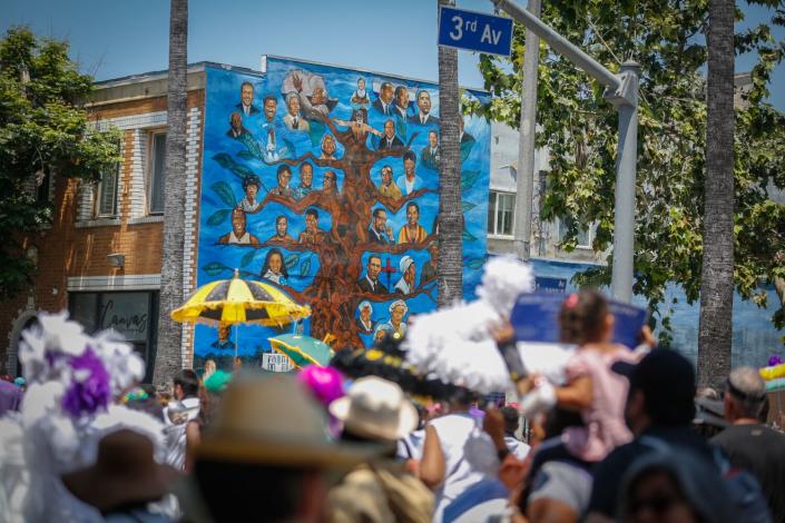 Community members celebrate the new name of "New Orleans Corridor"  pass a A mural of black leaders in Los Angeles.