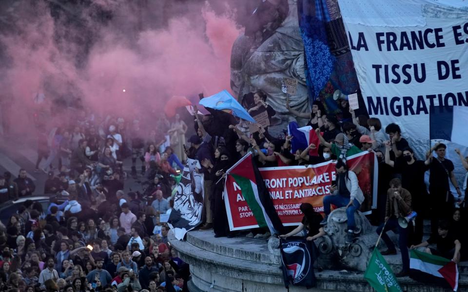 Crowds of people stand underneath a billowing cloud of pink smoke that has been released in celebration of the results