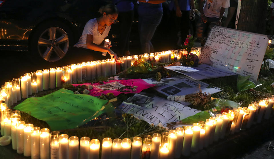 A woman adjusts candles during a vigil for Miya Marcano at Arden Villas, Friday, Oct. 1, 2021, in Orlando, Fla. The event was held outside the student's apartment. Orange County Sheriff John Mina said Saturday that authorities found Marcano’s body near an apartment building. Marcano vanished on the same day a maintenance man improperly used a master key to enter her apartment. (Chasity Maynard/Orlando Sentinel via AP)