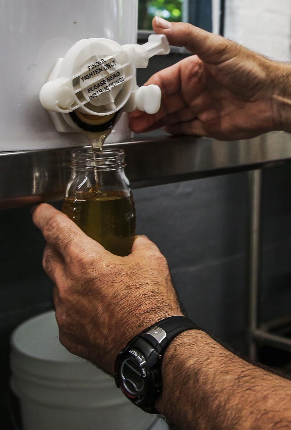 Cave Hill Cemetery head arborist/lead bee keeper Roger Martin, puts honey in a bottle while at Cave Hill Cemetery in Louisville on June 29, 2022.