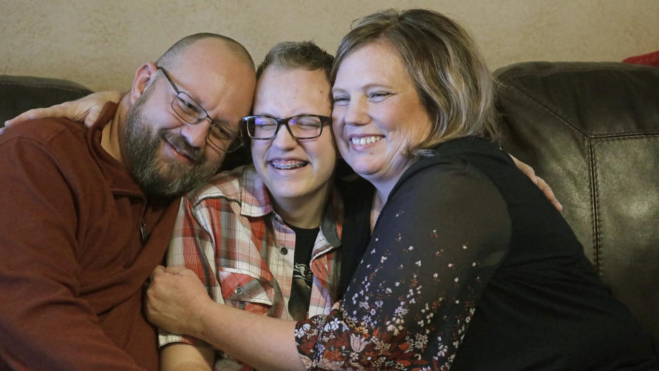 Dex Rumsey, 15, is photographed with his mother Robyn and father Clay Friday, Jan. 17, 2020, in Roy, Utah. Dex Rumsey, 15, came out as transgender at age 12. In consultation with a counselor and doctors, he gradually began wearing short hair and boy's clothes, then began using puberty blockers and eventually testosterone. His parents say he's gone from a shy, withdrawn child to a happy, thriving kid. He scared he could become depressed and suicidal again a ban on hormone therapy and sex-reassignment surgery for minors were to pass. (AP Photo/Rick Bowmer)