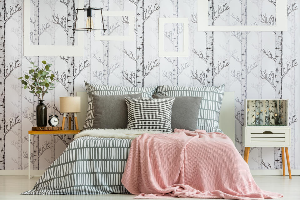 A bedroom scene with wallpaper decorated with trees.