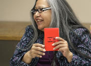 Annette Squetimkin-Anquoe, a member of the Colville Indian tribe and the Chief Traditional Health Officer at the Urban Indian Health Institute in Seattle, holds a booklet with a cover that reads "Passport to Tradition," Friday, Jan. 11, 2019, during a talking circle meeting to discuss the practice of traditional Indian medicine with employees of the Seattle Indian Health Board. Fallout from the federal government shutdown is hurting hundreds of Native American tribes and entities that serve them. The pain is especially deep in tribal communities with high rates of poverty and unemployment, and where one person often supports an extended family. (AP Photo/Ted S. Warren)