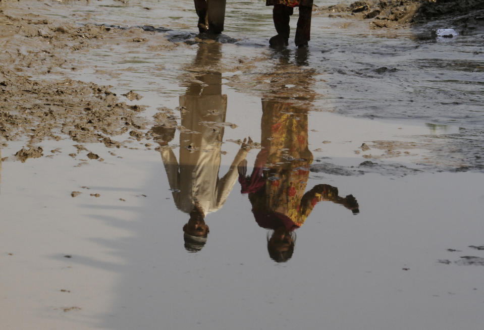 A boy and girl are reflected in water near their flood-hit home, in Charsadda, Pakistan, Wednesday, Aug. 31, 2022. Officials in Pakistan raised concerns Wednesday over the spread of waterborne diseases among thousands of flood victims as flood waters from powerful monsoon rains began to recede in many parts of the country. (AP Photo/Mohammad Sajjad)
