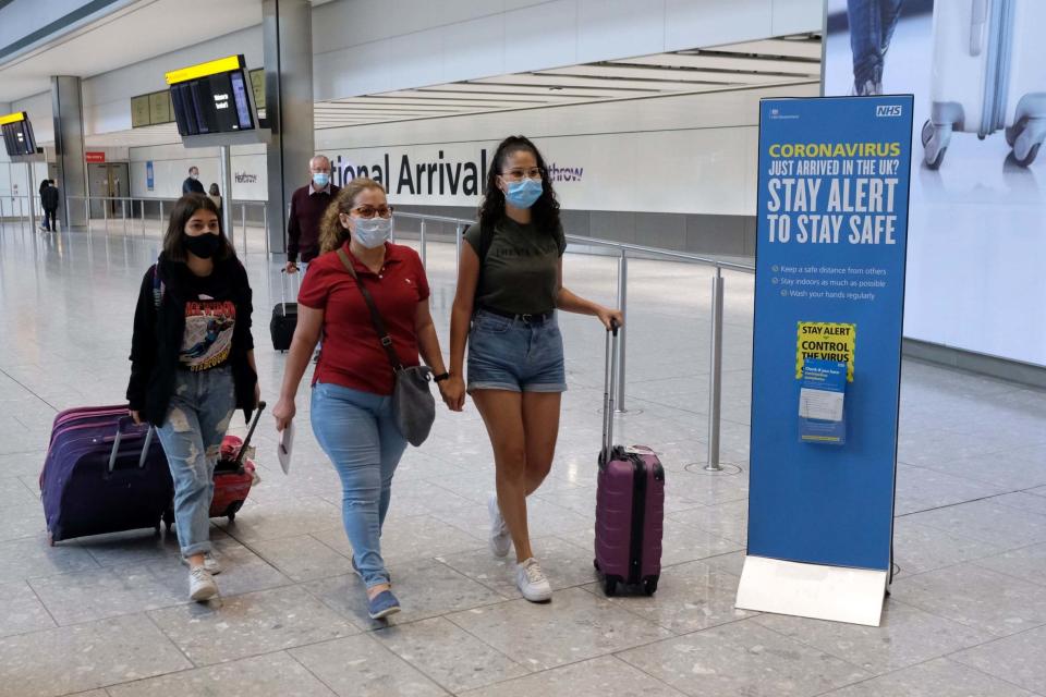 Travellers wear face masks as they make their way through Heathrow Airport (PA)
