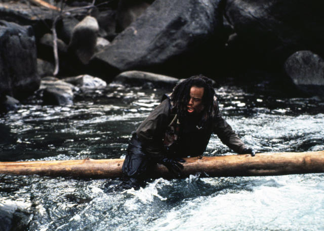 Ice-T crawls across a river on a large log