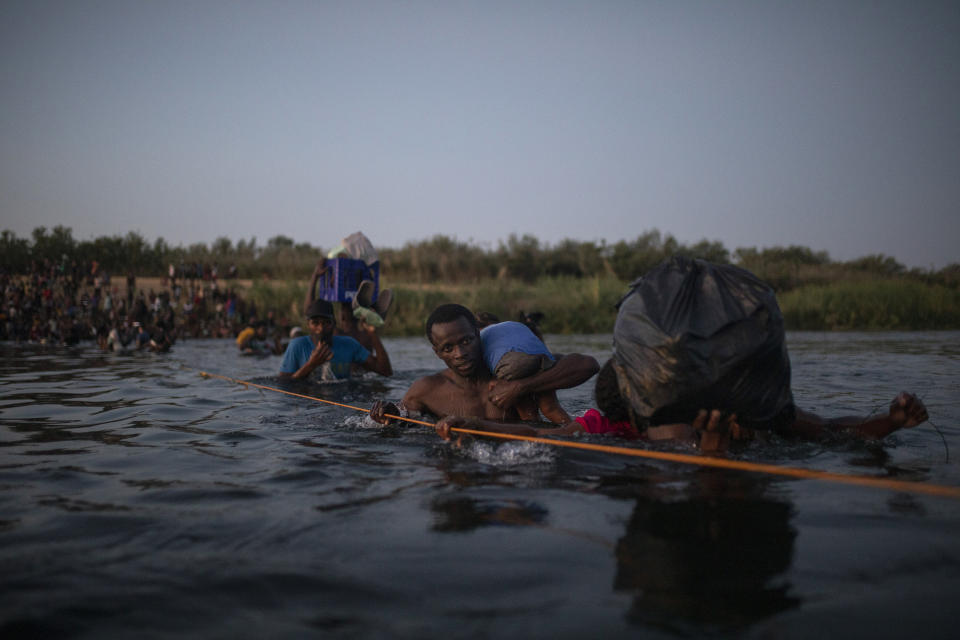 Migrants, many from Haiti, wade across the Rio Grande from Del Rio, Texas, to return to Ciudad Acuña, Mexico, late Sunday, Sept. 19, 2021, to avoid deportation to Haiti from the U.S. The U.S. is flying Haitians camped in a Texas border town back to their homeland and blocking others from crossing the border from Mexico in a massive show of force that signals the beginning of what could be one of America's swiftest, large-scale expulsions of migrants or refugees in decades. (AP Photo/Felix Marquez)