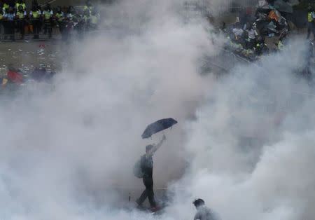 A protester walks in tear gas fired by riot policemen after thousands of protesters blocking the main street to the financial Central district outside the government headquarters in Hong Kong September 28, 2014. REUTERS/Stringer