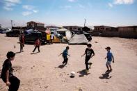 Un grupo de niños juega al fútbol en un campamento para refugiados en Iquique, al norte de Chile, el 3 de abril de 2014 (AFP | Juan Leonel)