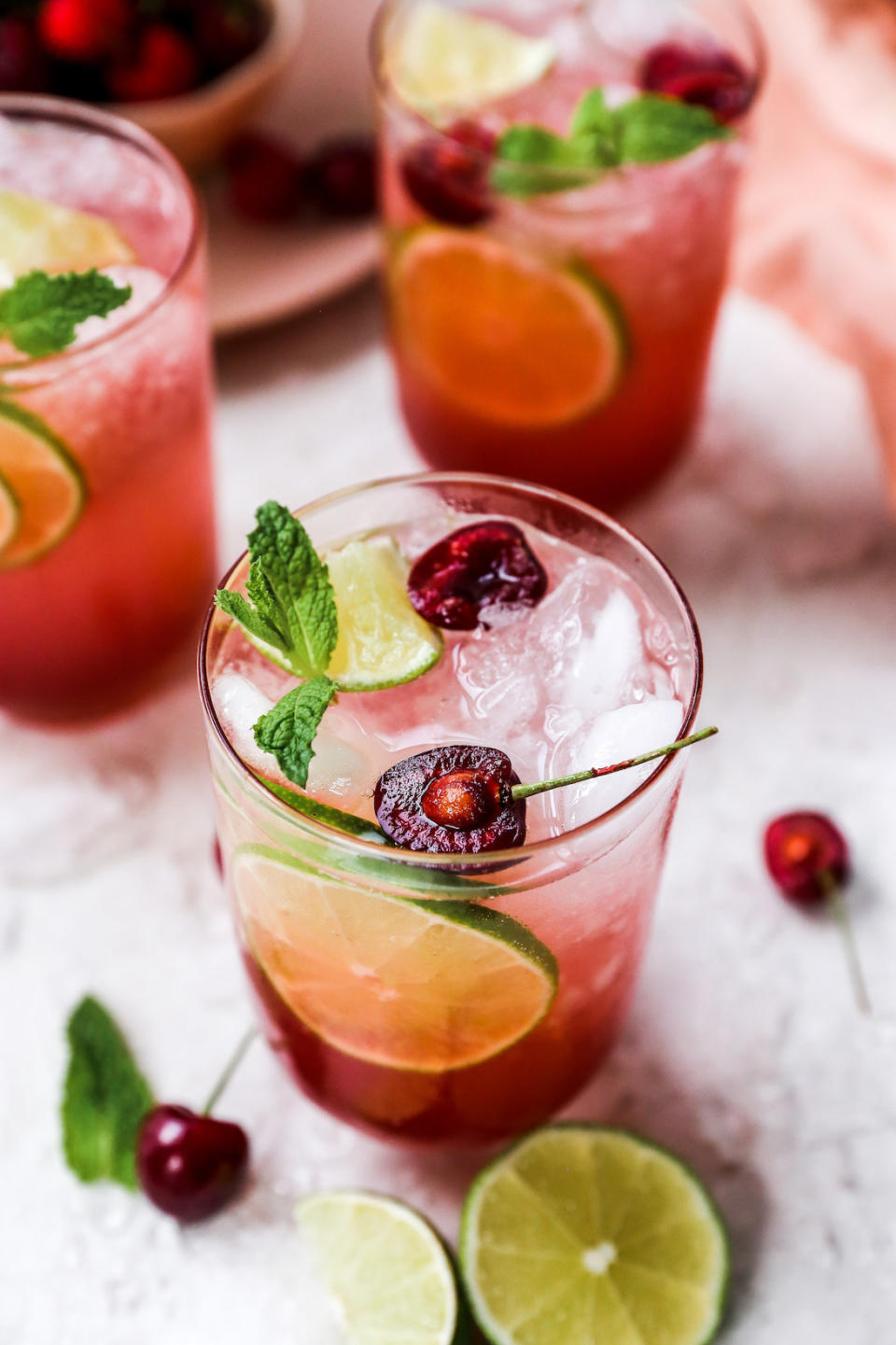 A cherry cocktail with sliced lime and mint.