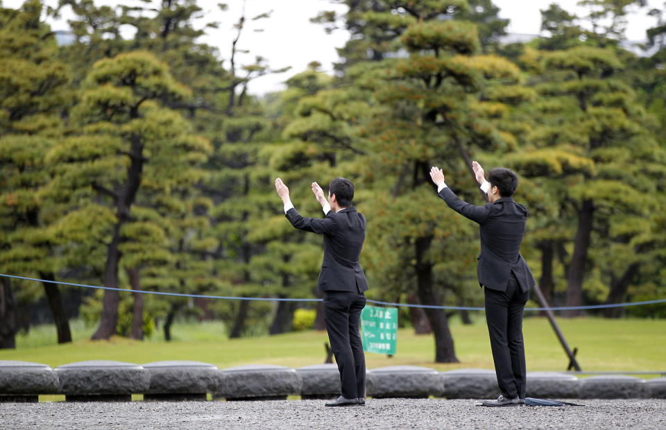 People raise their arms in the air toward Imperial Palace in Tokyo Wednesday, May 1, 2019. Japan has new Emperor Naruhito and he will perform his first ritual hours after succeeding the Chrysanthemum Throne from his father Akihito who abdicated the night before. (AP Photo/Eugene Hoshiko)