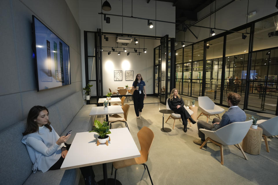 People sit in a waiting lounge at the new Electrify America indoor electric vehicle charging station in San Francisco, Wednesday, Feb. 7, 2024. Electrify America, Tesla, Mercedes and other charging networks are starting to build nicer spots for people to fill up their electric vehicles, knowing they'll be there for a lot longer than people spend at gas stations. (AP Photo/Eric Risberg)