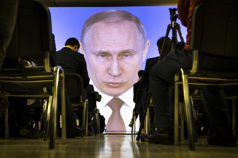 FILE - In this Thursday, March 1, 2018 file photo journalists watch as Russian President Vladimir Putin gives his annual state of the nation address in Manezh in Moscow, Russia. Putin set a slew of ambitious economic goals, vowing to boost living standards, improve health care and education and build modern infrastructure in a state-of-the-nation address. (AP Photo/Alexander Zemlianichenko, File)