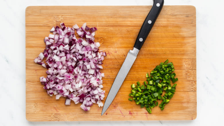 Chopped red onion and jalapeno on board