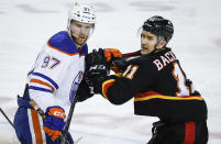 Edmonton Oilers forward Connor McDavid (97) holds the jersey of Calgary Flames forward Mikael Backlund (11) during the third period of an NHL hockey game Saturday, April 6, 2024, in Calgary, Alberta. (Jeff McIntosh/The Canadian Press via AP)