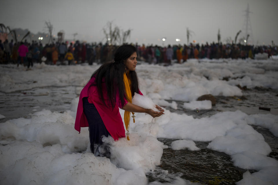 A Hindu devotee playfully grabs a handful of chemical foam floating in Yamuna river during Chhath Puja festival in New Delhi, India, Wednesday, Nov. 10, 2021. A vast stretch of one of India's most sacred rivers, the Yamuna, is covered with toxic foam, caused partly by high pollutants discharged from industries ringing the capital New Delhi. Still, hundreds of Hindu devotees Wednesday stood knee-deep in its frothy, toxic waters, sometimes even immersing themselves in the river for a holy dip, to mark the festival of Chhath Puja. (AP Photo/Altaf Qadri)