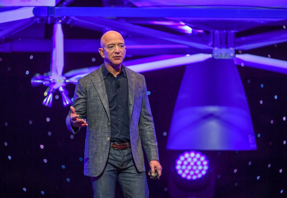 Jeff Bezos speaks with his lunar lander hovering in the background.