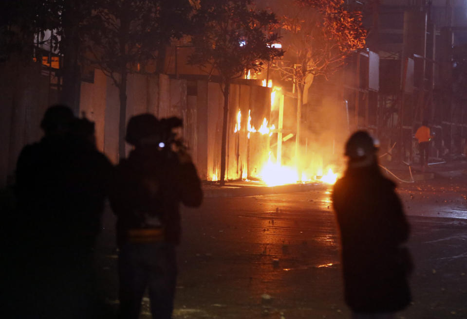 Hezbollah and Amal supporters set fire to trees in Beirut, Lebanon, Tuesday, Dec. 17, 2019. Supporters of Lebanon's two main Shiite groups Hezbollah and Amal have clashed with security forces and set fire to cars in Beirut in a third consecutive night of violence in the capital. The unrest early Tuesday apparently was triggered by a video circulating online that shows a man insulting Shiite and religious figures. (AP Photo/Bilal Hussein)