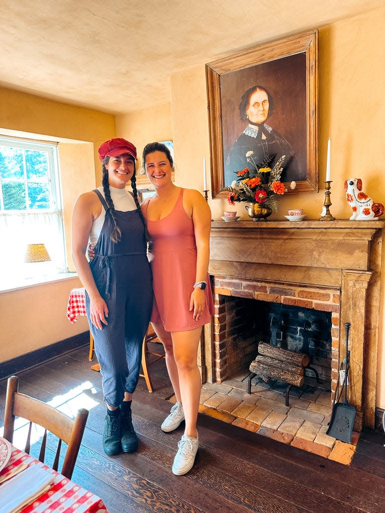 Haley Dolata, left, and Julia Silvers pose in front of a painting at Wisconsin historical site Pendarvis in Mineral Point during a Wisconsin history road trip.