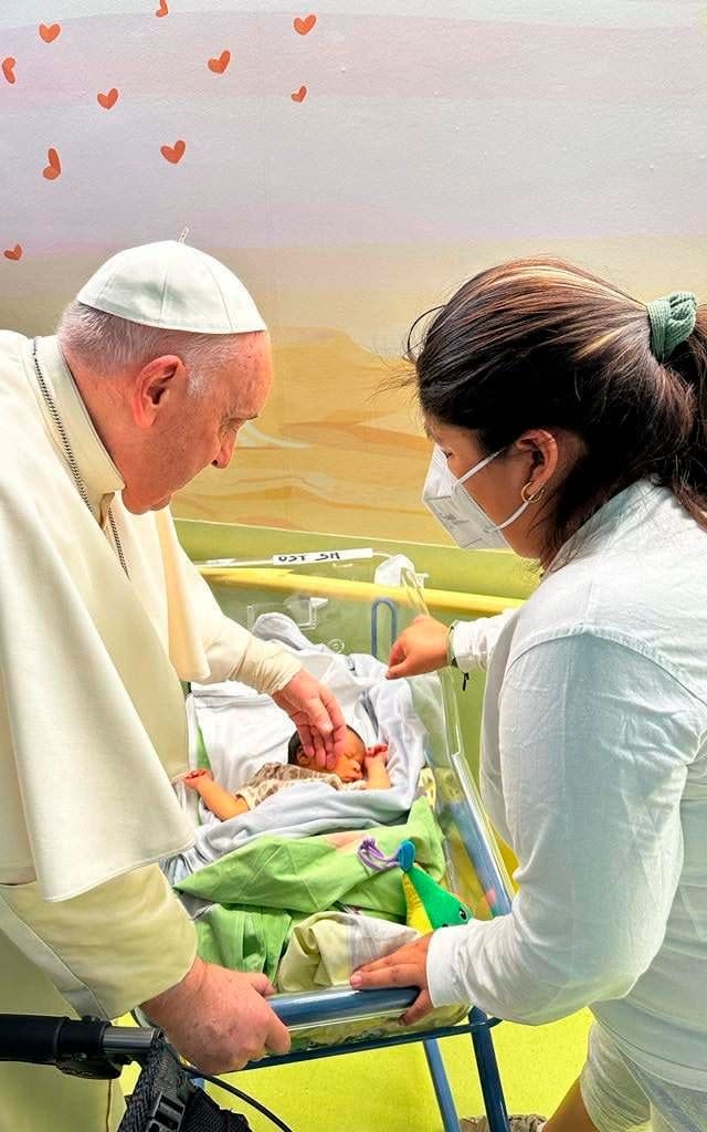 Pope Francis caresses an infant before baptising him with the name of Miguel Angel - Vatican Media