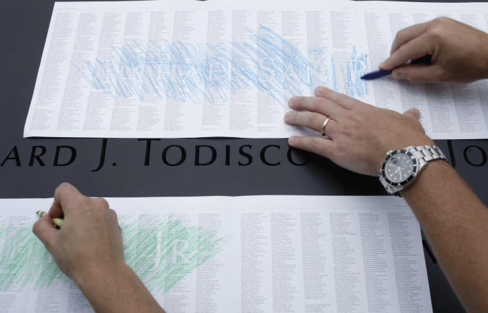 Visitors at the Sept. 11 memorial make impressions of specific names over a master list of the names of those killed in the 2001 terrorist attacks on the World Trade Center, Sunday, Sept. 11, 2011 in New York. (AP Photo/Seth Wenig, Pool)