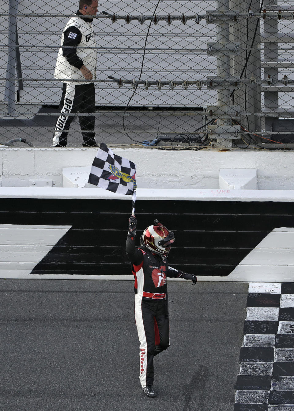 Michael Annett waves the checkered flag after getting it from a race official at the end of the NASCAR Xfinity auto race Saturday, Feb. 16, 2019, at Daytona International Speedway in Daytona Beach, Fla. Annett won the race. (AP Photo/Chris O'Meara)