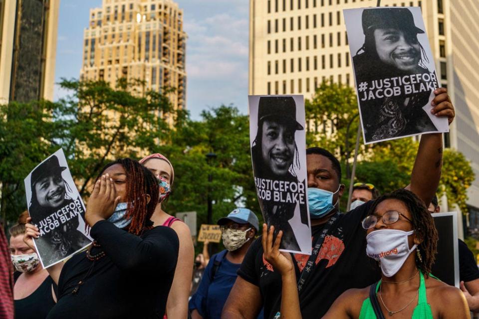 Protesters hold signs outside the Minneapolis 1st Police precinct during a demonstration against police brutality and racismÂ on August 24, 2020 in Minneapolis, Minnesota. - It was the second day of demonstrations in Kenosha after video circulated Sunday showing the shooting of Jacob Blake -- multiple times, in the back, as he tried to get in his car, with his three children watching. (Photo by Kerem Yucel / AFP) (Photo by KEREM YUCEL/AFP via Getty Images)