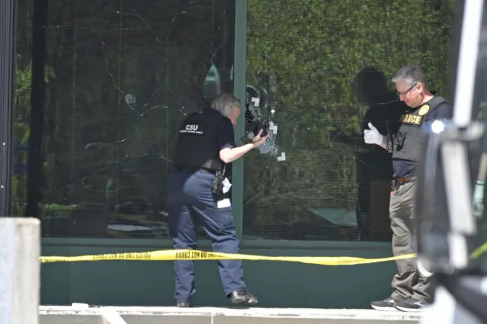 A Louisville Metro Police technician photographs bullet holes in the front glass of the Old National Bank building on April 10, 2023, in Louisville, Kentucky. A shooting at the bank killed and wounded several people, police said. The suspected shooter was also dead. (AP Photo/Timothy D. Easley)