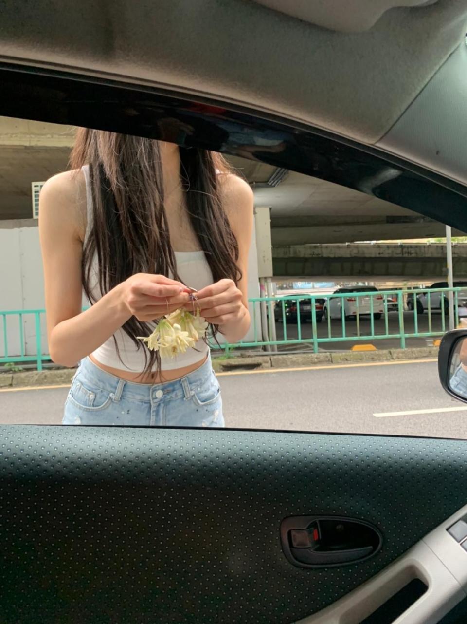 一位長髮飄逸的正妹穿著白色小背心和熱褲，在車陣中行走兜售玉蘭花。（圖／翻攝自臉書「爆廢1公社」）