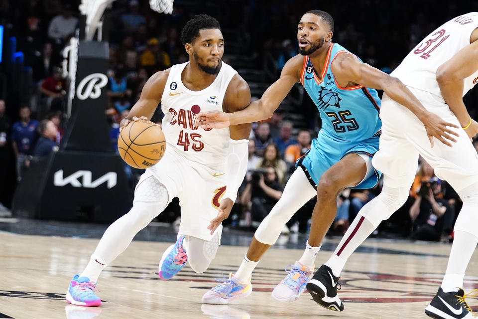 Cleveland Cavaliers' Donovan Mitchell (45) drives around Phoenix Suns' Mikel Bridges (25) during the first half of an NBA basketball game in Phoenix, Sunday, Jan. 8, 2023. (AP Photo/Darryl Webb)