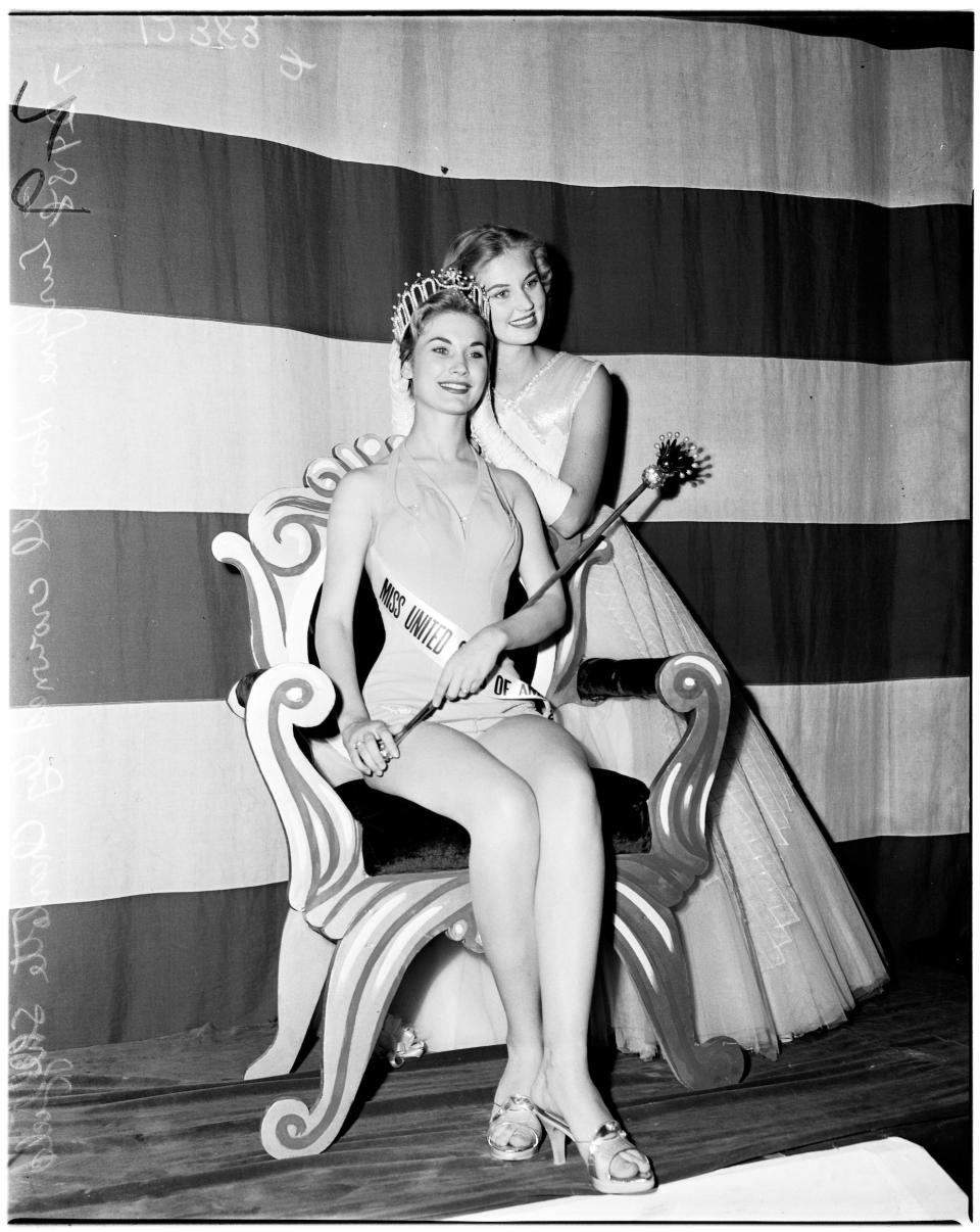 Miss USA 1958 Eurlyne Howell poses on her throne with a scepter and wearing a tiara.