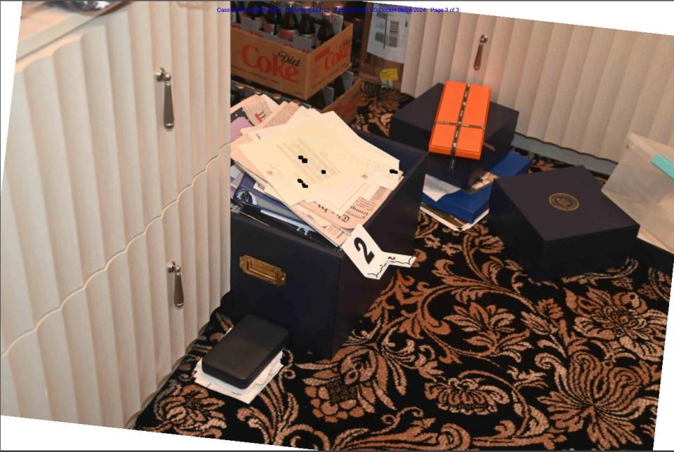 This DOJ evidence photo shows a box containing classified documents on the floor of a Mar-a-Lago storage room, next to gifts and a case of Diet Coke.