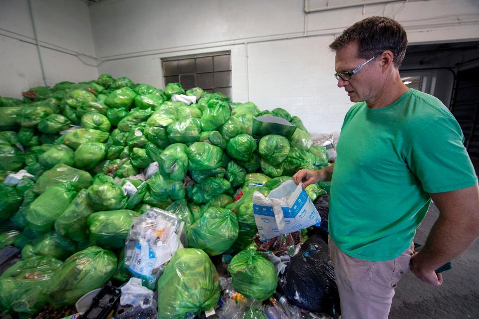 Ross Gibby, chief operating officer for CRDC global,  looks at a plastic mailing bag that would normally not be considered recyclable at CRDC's new processing plant in York. The green bags were part of a pilot project in a community where households packed up combined plastic recycling.