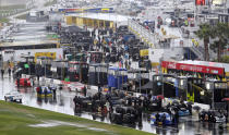 Crew members push cars into the garage after NASCAR postponed the Daytona 500 auto race in Daytona Beach, Fla., Sunday, Feb. 26, 2012, due to rain. The race has been rescheduled for Monday afternoon. (AP Photo/David Graham)