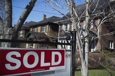 A sold sign in front of a large house.