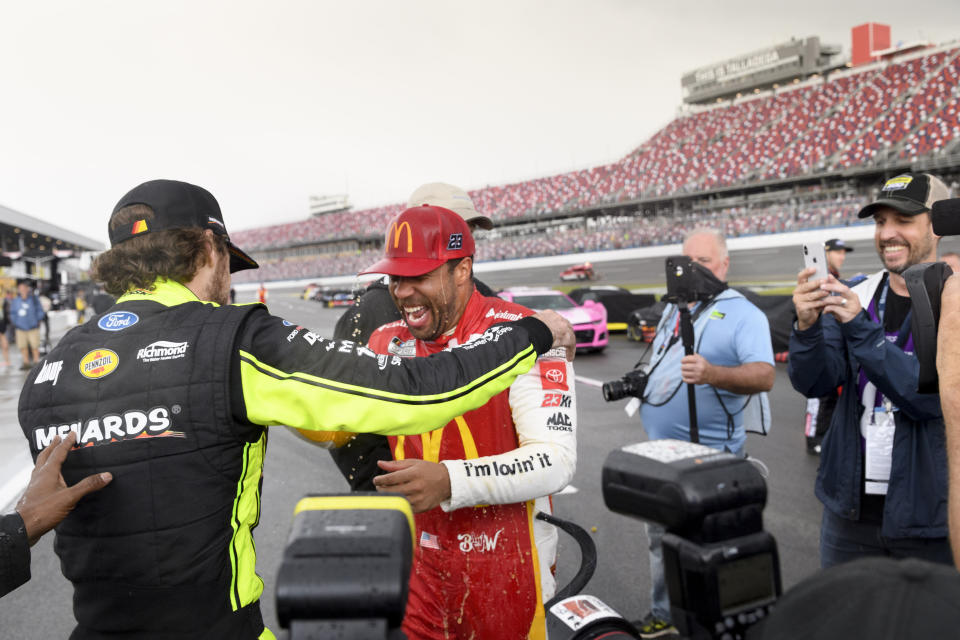 Bubba Wallace, second from left, is congratulated by Ryan Blaney, left, after Wallace was pronounced the winner while on pit row during a rain delay in a NASCAR Cup series auto race Monday, Oct. 4, 2021, in Talladega, Ala. (AP Photo/John Amis)