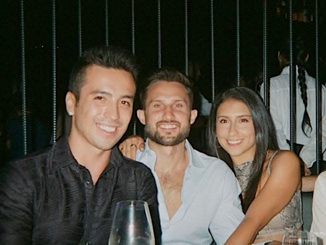 Jamie, Tyler, and Camila out at a bar with cocktails on the table.