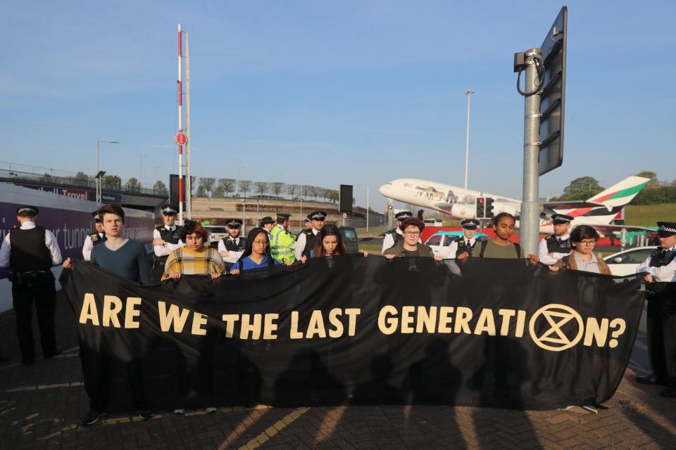 Climate change activists hold a banner as they attend an Extinction Rebellion protest outside Heathrow Airport (REUTERS)