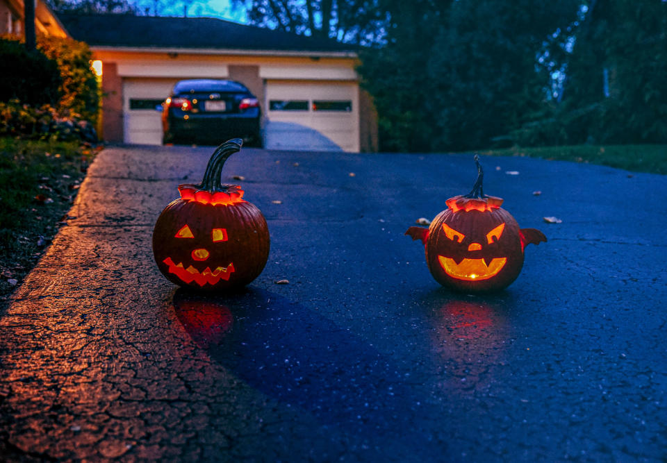 freebie OAKWOOD, OHIO, UNITED STATES - 2020/10/31: Two jack-o-lanterns glow on a driveway as the sun sets during Oakwood's first 