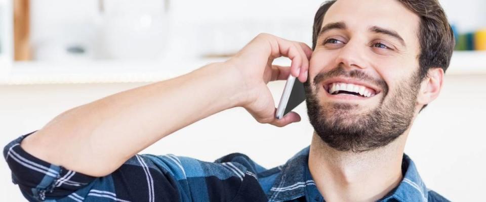 A man is talking on the phone and smiling at work