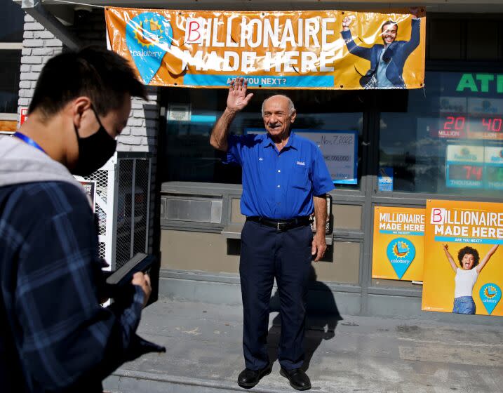 ALTADENA, CA - NOVEMBER 09: Joseph Chahayed, 74, right, owner of Joe's Service Station, now an ExxonMobil franchise, sold the winning Powerball ticket worth more than $2 billion, waves to a customer while giving an interview to a news organization on Wednesday, Nov. 9, 2022 in Altadena, CA. Chahayed will be receiving a $1-million bonus check for selling the $2.04-billion jackpot-winning ticket. (Gary Coronado / Los Angeles Times)