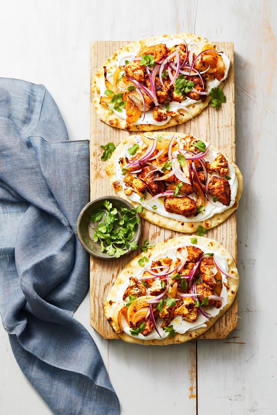 tandoori spiced cauliflower chicken flatbreads on a wooden plank