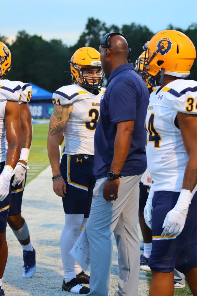 Dialleo Burks, pictured here in the middle, coaches up his team. Burks, a former NFL player, is in his first year with Warner as the head coach.